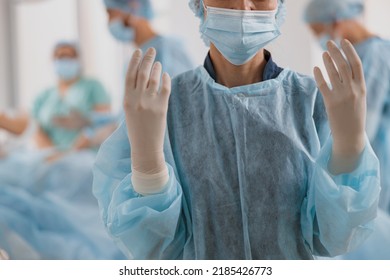 Close Up Of Female Surgeon In Mask And Gloves Standing In Operating Room, Ready To Work On Patient