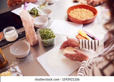 Close Up Of Female Teacher Demonstrating How To Use Dough To Make Flatbread In Cookery Class