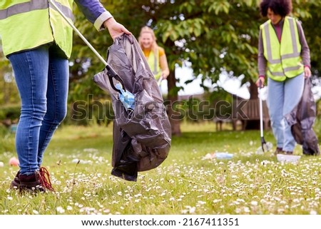 Close Up Of Female Volunteers Picking Up Litter In The Countryside