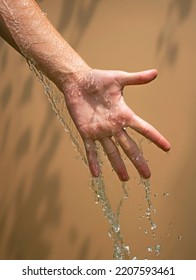 Close Up Of A Female Wet Hand With Water Gliding Over It On A Beige Background, Outdoor Shot.