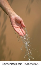 Close Up Of A Female Wet Hand With Water Gliding Over It On A Beige Background, Outdoor Shot.