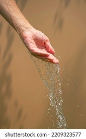 Close Up Of A Female Wet Hand With Water Gliding Over It On A Beige Background, Outdoor Shot.