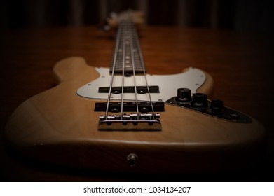 Close up of a fender electric jazz bass with wood color and pick guard