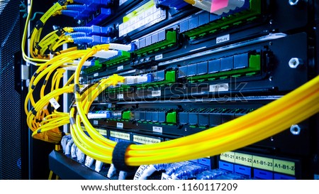 Close up fiber optic in server room , network cables installed in the rack. yellow and blue 