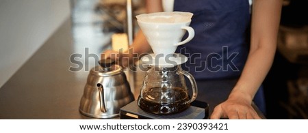 Close up of filter coffee brewing kit and kettle, cafe barista preparing filter at the counter.