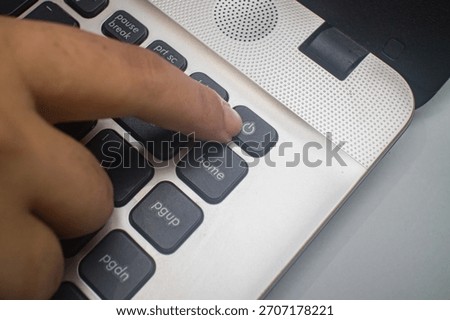 A close up of a finger pressing the Power button on a laptop keyboard, illustrates the concepts of turning on devices in everyday digital work. technology, and computing activity.