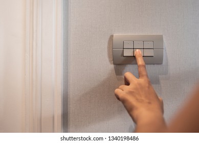 Close up of finger is turning on or off on grey light switch. Copy space.