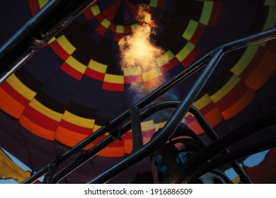 Close Up To Fire Inside A Hot Air Ballon Being Inflated With The Blue Sky Behind. 