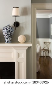 Close Up Of A Fireplace Mantle With A Vase And Lighting Fixture.