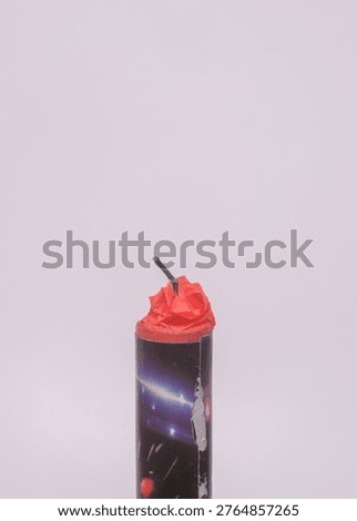Close up of a firework cracker with fuse isolated on white background. A detailed shot of the top of a cylindrical firework featuring a black fuse and red paper seal. This pyrotechnic object is isolated against a plain light background. It is commonly used for celebrations and festivals