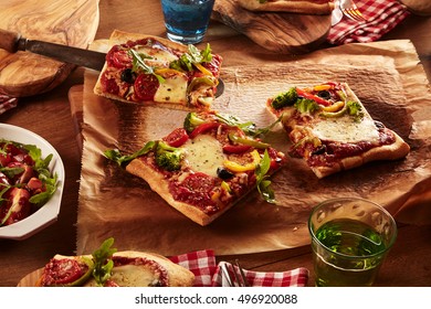 Close Up First Person Perspective View On Pizza And Salad Dinner Served On Wooden Board