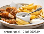 Close up of Fish and Chips on a plate served with mayonnaise and tartar sauce