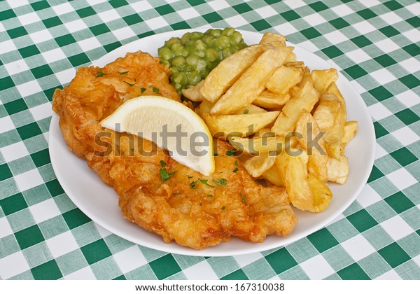 Close up of fish\
and fries garnished with mushy peas and a slice of lemon, on a\
traditional Diner table\
top.