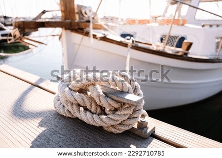 A close up of a fishing boat moored in a harbour, secured by an anchor and rope to a dock bollard. Nautical vessel used for maritime transport and the work of fishermen.