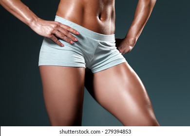 Close up of fit woman's torso with her hands on hips. Perfect quadriceps muscle/Female with perfect abdomen and quadriceps muscles