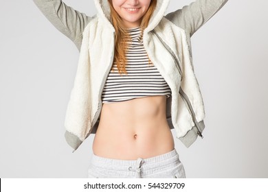 Close up of fit woman's torso with her hands up. Female with perfect abdomen muscles on grey background