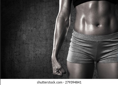 Close up of fit woman's torso. Woman with clenched fist and perfect abdomen muscle/Strength