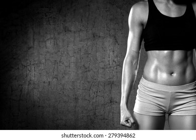 Close up of fit woman's torso. Woman with clenched fist and perfect abdomen muscle/Strength 