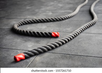 Close up of fitness battle ropes lie on black floor in fitness gym. Sport and fitness equipment. Functional training.