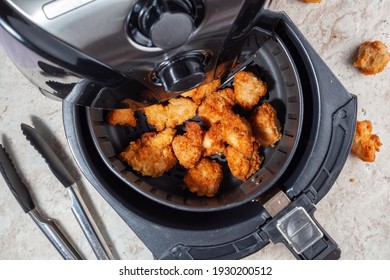 Close up flat lay image of an air fryer oven on kitchen countertop. This offers fast and easy crispy food with little or no fat by circulating hot air inside the basket. A healthy snack alternative.