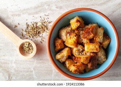 Close up flat lay image of home made croutons in a bowl. Bread cubes were baked to crisp in oven and dipped into olive oil or butter and finished with Italian seasoning. Used as a versatile garnish.