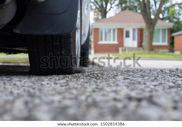 Close up of flat rear
tire of white suv track car vehicle automobile punctured by nail.
Summer day, residential street. Selective focus, depth of field,
space for copy.