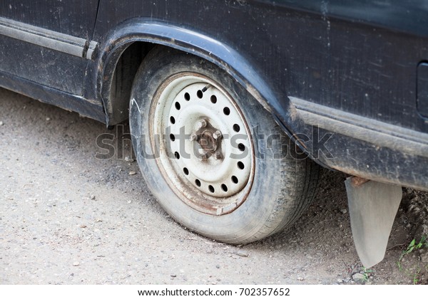 Close up Flat tire and old car on the road\
waiting for repair. Broken\
concept