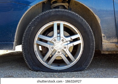 Close Up Of A Flat Tire Of A Rusty Old Blue Car Centered On Gravel Road