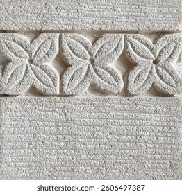 Close up of flower shape pattern carved on a white limestone. Seamless floral embossed stone background texture. Exotic feel.
