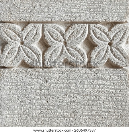 Close up of flower shape pattern carved on a white limestone. Seamless floral embossed stone background texture. Exotic feel.