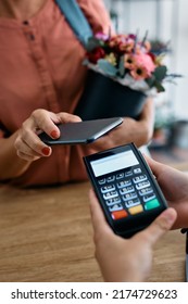 Close Up Of Flower Shop Customer Using Smart Phone And Paying Contactless For Flower Box.