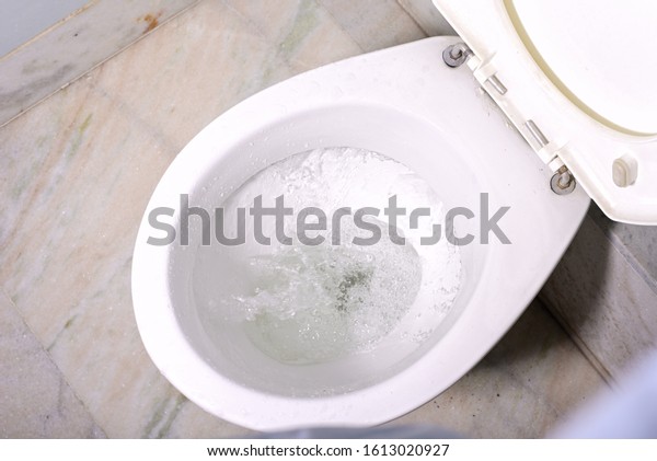 Close up flushing\
water in clean toilet\
bowl.