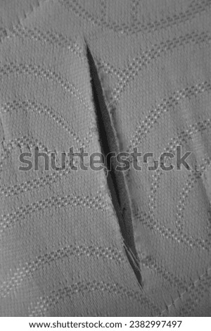 close up of a foam mattress with one big hole, torn, damaged. foam sofa texture for background. material texture with torn white threads on white foam rubber. 