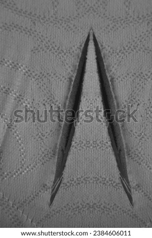 close up of a foam mattress with one big hole, torn, damaged. foam sofa texture for background. material texture with torn white threads on white foam rubber. 