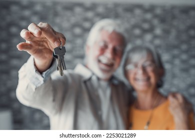 Close up focus of happy old Caucasian couple show keys to own apartment or house. Smiling mature retired man and woman celebrate relocation to new home. Moving, rental, estate concept. - Shutterstock ID 2253021289
