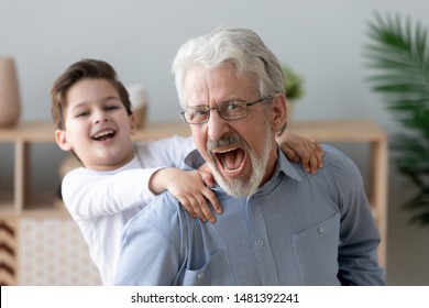 Close up focus laughing grandfather give piggyback ride little grandson, grandad carried on back adorable grandkid, next generation, multi generational men having deep connection understanding concept