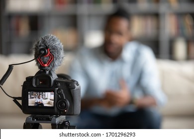 Close up focus of modern professional camera shooting african American male coach or tutor making vlog, biracial man blogger talk with subscribers record video tutorial on web cam, technology concept