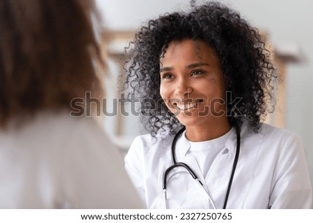 Close up focus on African smiling woman doctor in white coat stethoscope on neck look at patient listen examine health. Adolescent medicine hebiatrics or paediatrics, healthcare medical worker concept