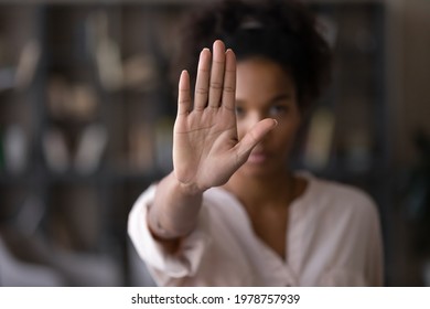 Close up focus on female mixed race palm hand showing stop sign, serious african american woman protesting against bullying in society, sexual or racial discrimination, denying family abuse indoors. - Shutterstock ID 1978757939