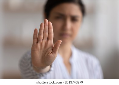 Close up focus on Indian woman showing stop gesture at camera, blurred background, strong young female protesting against domestic violence and abuse, bullying, saying no to gender discrimination