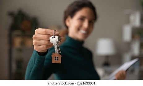 Close up focus on keys, smiling woman realtor selling apartment, offering to client, showing at camera, holding documents, contract, making purchasing deal, real estate agent, mortgage or rent - Powered by Shutterstock