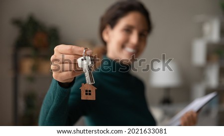 Close up focus on keys, smiling woman realtor selling apartment, offering to client, showing at camera, holding documents, contract, making purchasing deal, real estate agent, mortgage or rent