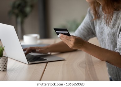 Close up focus on plastic bank card in female hands, young woman entering payment information or cvv code in computer online banking application, transferring electronic money or shopping indoors.