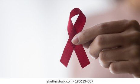 Close up focus on red ribbon in female hands, symbol of fighting against HIV AIDS breast cancer, drugs or alcohol addiction, sign of ill people support, regular medical checkup promotion, copy space.