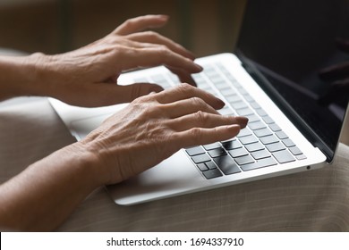 Close Up Focus On Wrinkled Female Hands Typing Message On Laptop Keyboard. Middle Aged Older Woman Working On Architect Building Project, Sharing Pictures Chatting Communicating In Social Network.