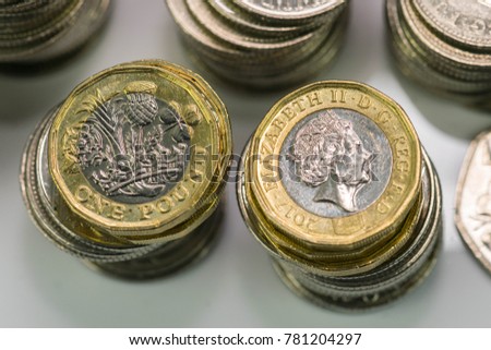Close up focus photos of new United kingdom Pound coin, among other British coins