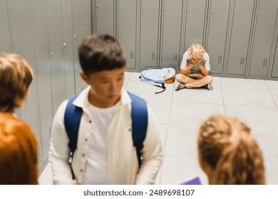 Close up focused lonely sad schoolboy crying at the school hall floor while his classmates ignoring him. Bullying at school problem. Social exclusion concept - Powered by Shutterstock