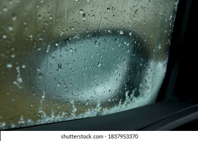 close up of fogged up car wing mirror looking through car window with snow and water droplets on glass in bad weather conditions in winter 