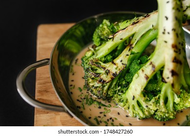 Nahaufnahme von Lebensmitteln von grünem Broccoli zuerst gegrillt, dann mit Sesam und Südsoße in einer Stahlpfanne gebraten