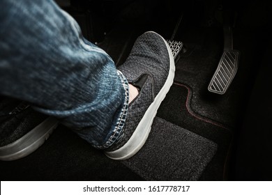 Close up the foot pressing brake pedal of a car. Driver stopping the car.